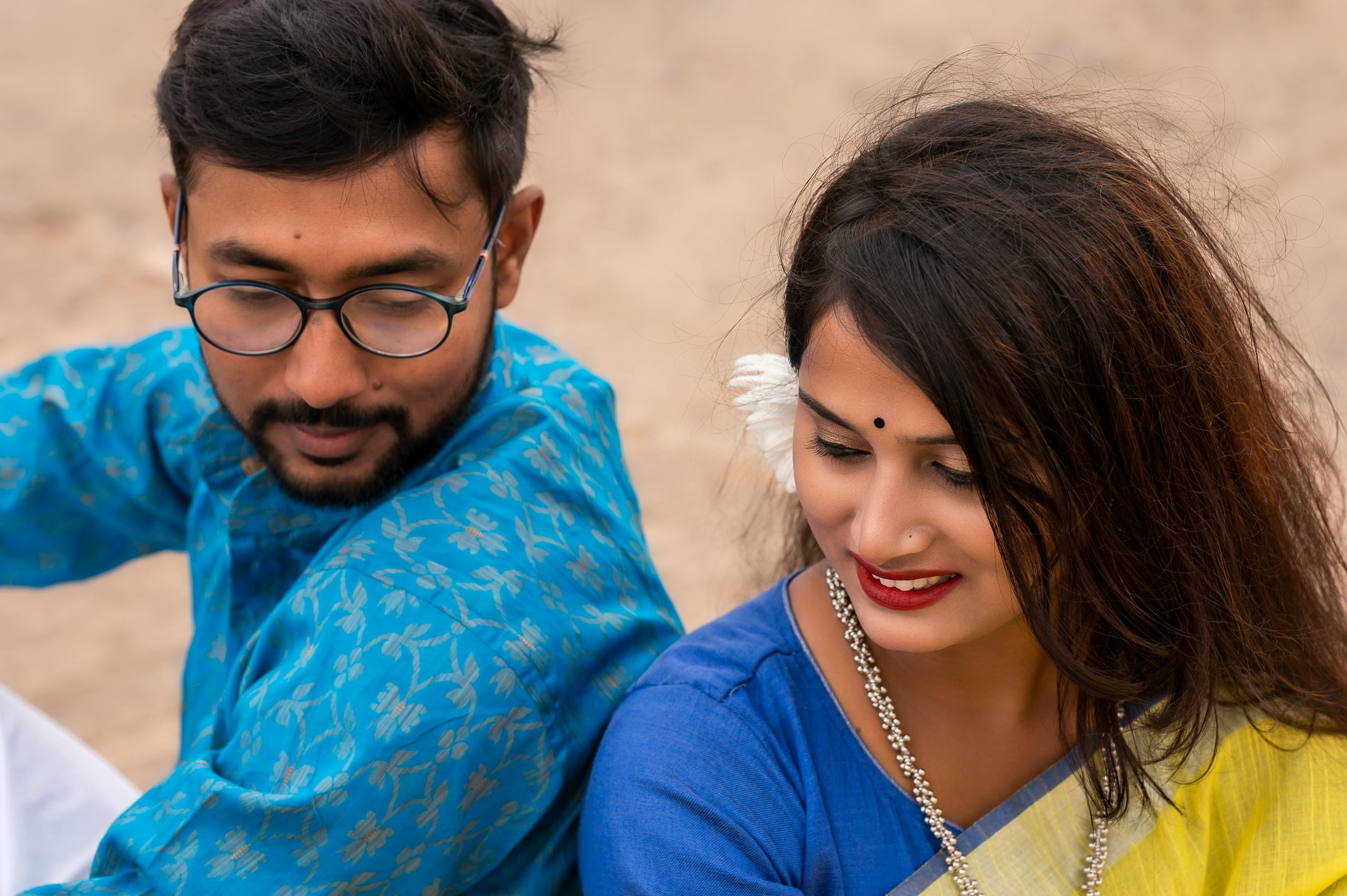 A couple in traditional Indian attire sharing a candid moment outdoors.